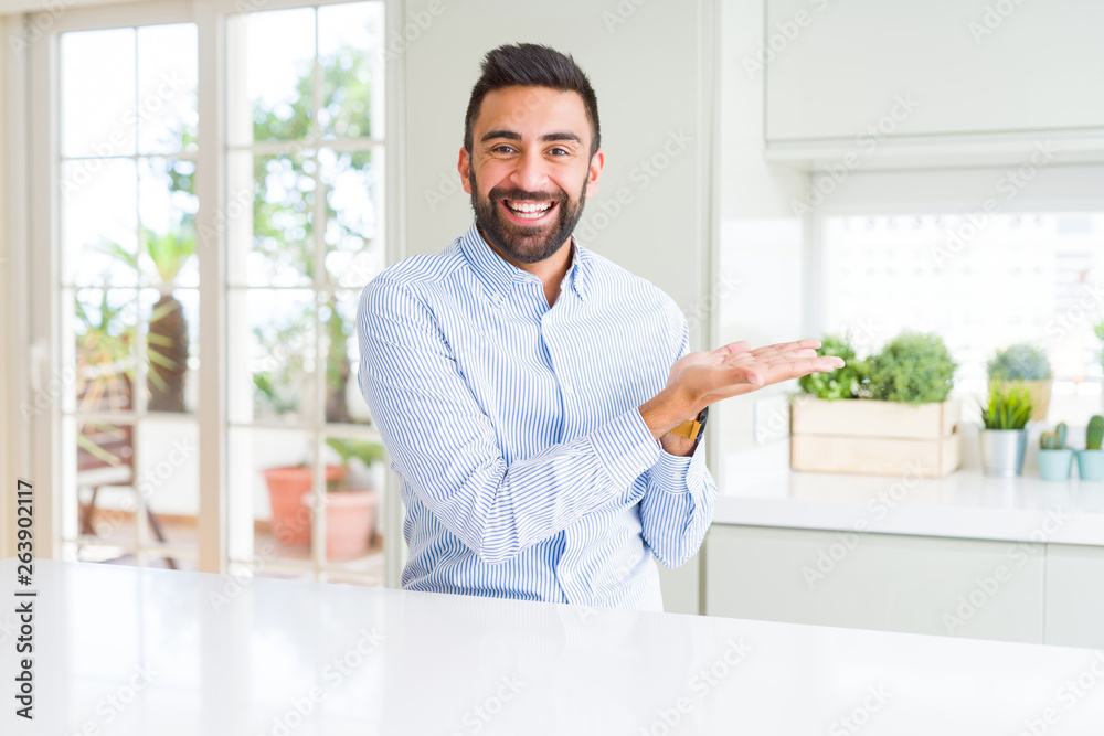 Handsome hispanic business man Pointing to the side with hand and open palm, presenting ad smiling happy and confident