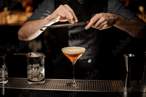Bartender making an alcohol cocktail using grater