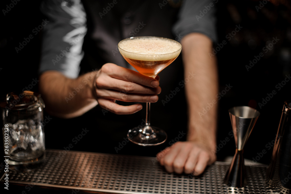 Close shot of bartender holding cocktail with foam
