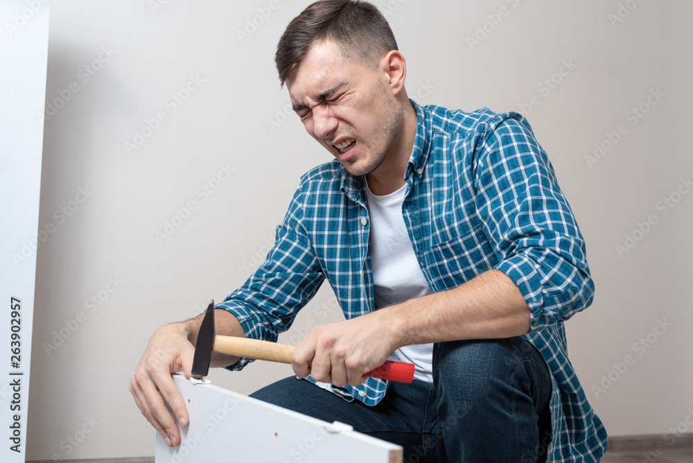 man hit his thumb with hammer assembling furniture man hit his thumb with hammer assembling furniture