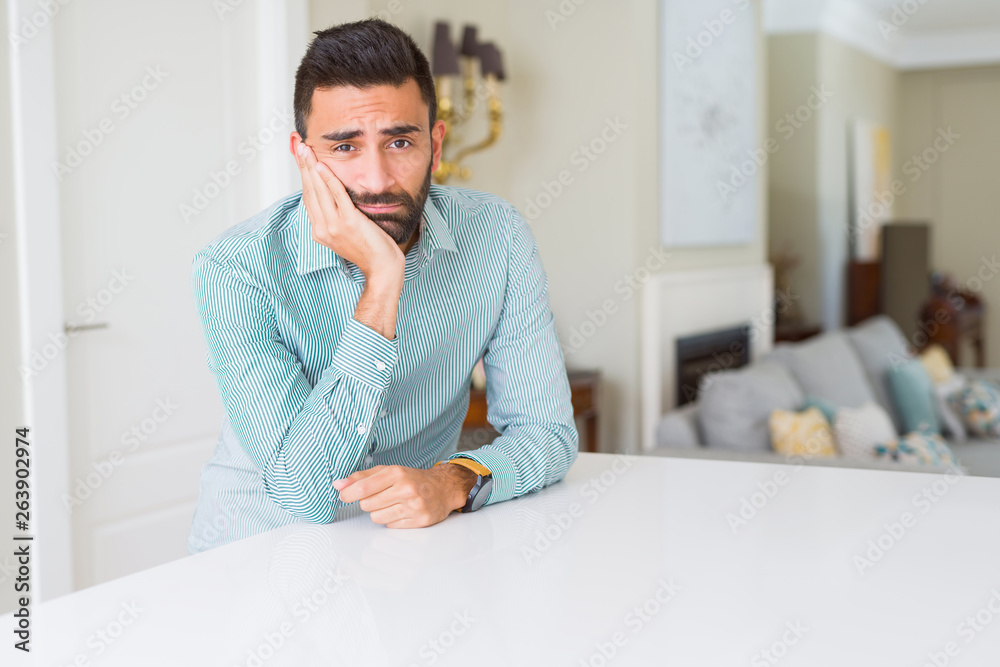 Handsome hispanic man at home thinking looking tired and bored with depression problems with crossed arms.