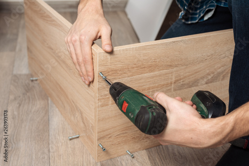 Assembling furniture. Men's hands with a screwdriver to collect new furniture photo