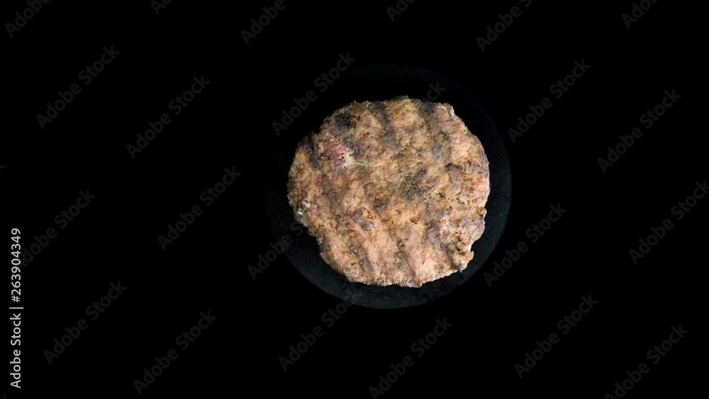 Cutlet from burgers rotates on an black background, cooking Round patty, top view