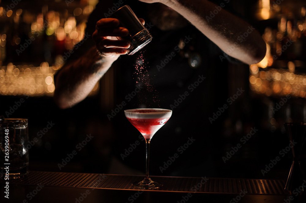 Bartender sprinkles the alcohol cocktail in glass