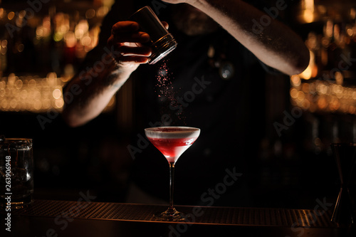 Bartender sprinkles the alcohol cocktail in glass