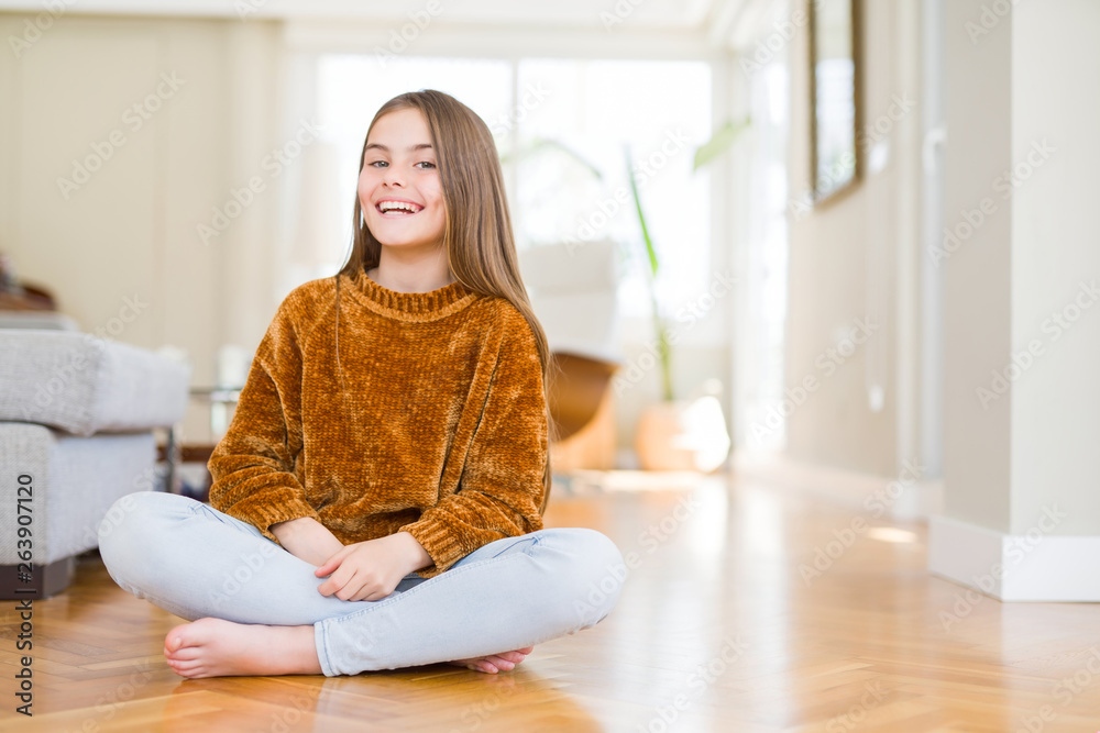 Beautiful young girl kid sitting on the floor at home with a happy and cool smile on face. Lucky person. Beautiful young girl kid sitting on the floor at home with a happy and cool smile on face. Lucky person.