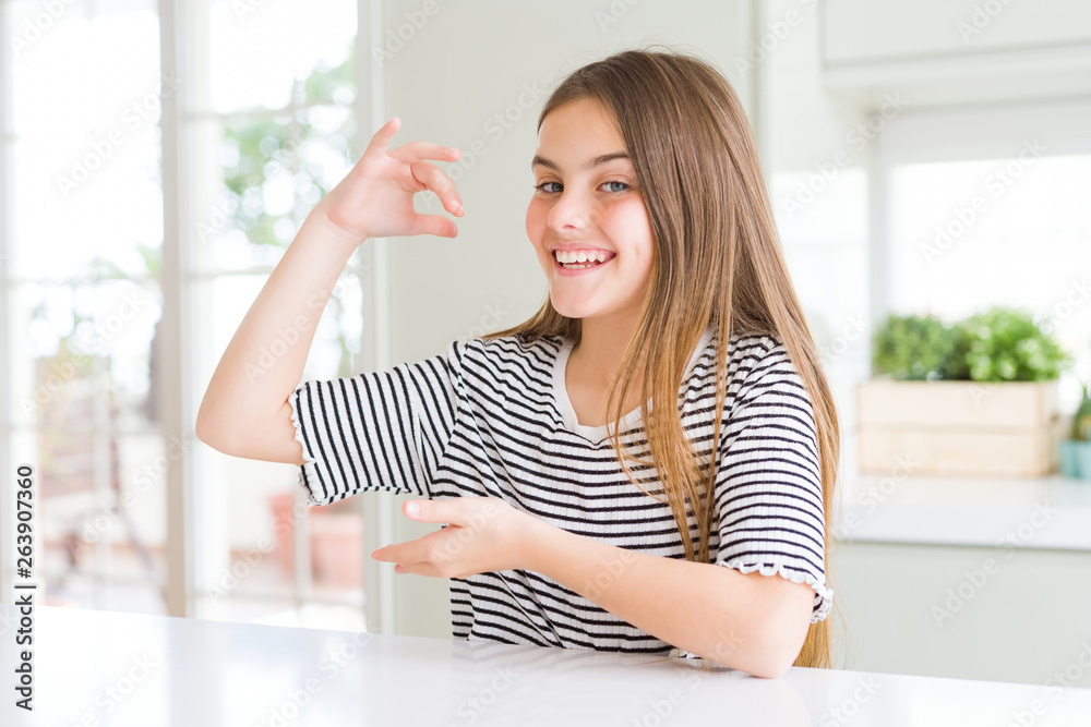 Beautiful young girl kid wearing stripes t-shirt gesturing with hands showing big and large size sign, measure symbol. Smiling looking at the camera. Measuring concept. Beautiful young girl kid wearing stripes t-shirt gesturing with hands showing big and large size sign, measure symbol. Smiling looking at the camera. Measuring concept.