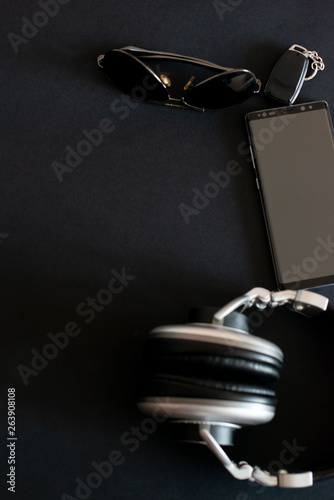 headphones smartphone sunglasses on a black background