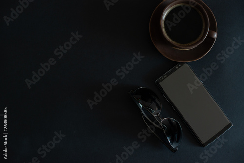 cup of coffee, sun glasses, smartphone on a black background