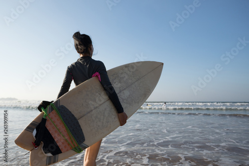 Photography Woman surfer with surfboard going to surf