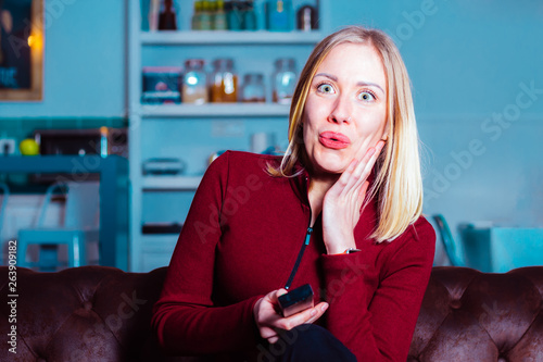Surprised young woman watching something shocking on tv