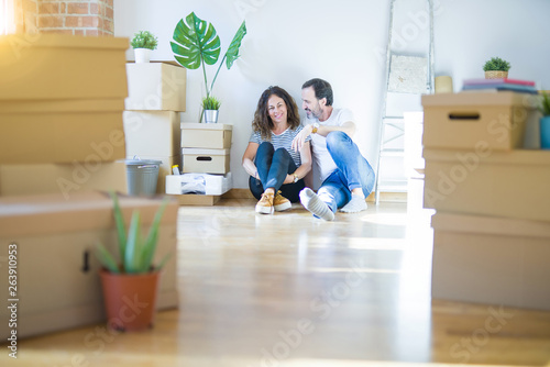 Middle age senior romantic couple in love sitting on the apartment floor with cardboard boxes around and smiling happy for moving to a new home © Krakenimages.com