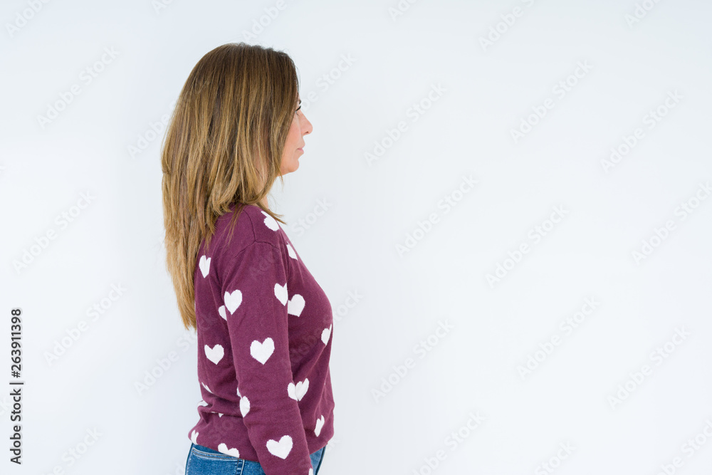 Beautiful middle age woman wearing heart sweater over isolated background looking to side, relax profile pose with natural face with confident smile. Beautiful middle age woman wearing heart sweater over isolated background looking to side, relax profile pose with natural face with confident smile.