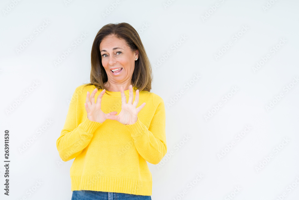 Beautiful middle age woman wearing yellow sweater over isolated background disgusted expression, displeased and fearful doing disgust face because aversion reaction. With hands raised