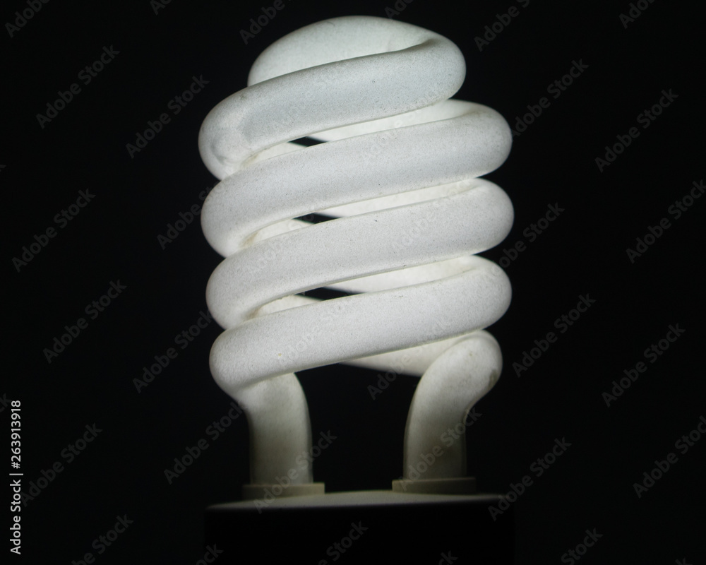 A white energy saving bulb and blacked background. A white energy saving bulb and blacked background.