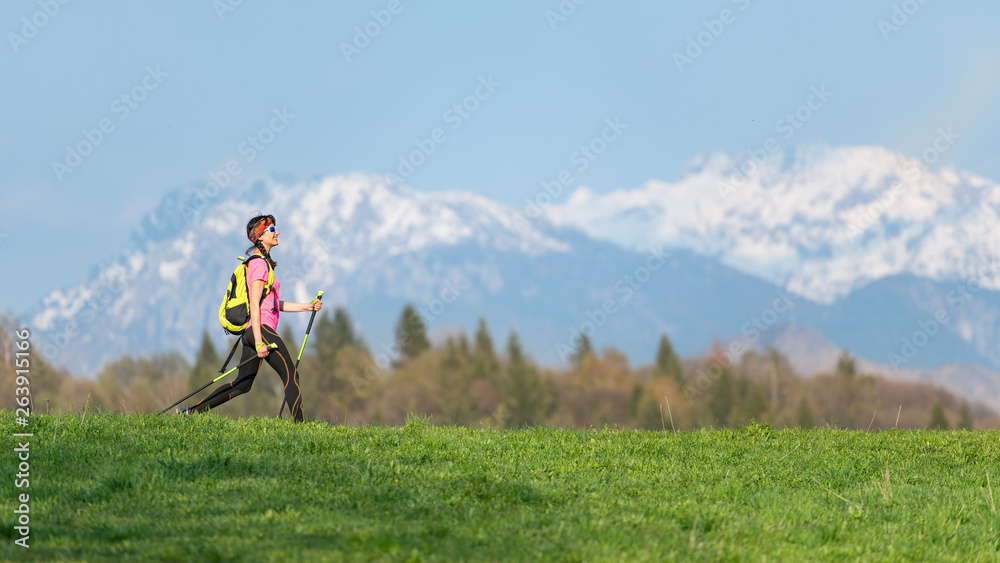 Girl hiking in the mountains with spring contrasts of green meadows and snow on the mountains