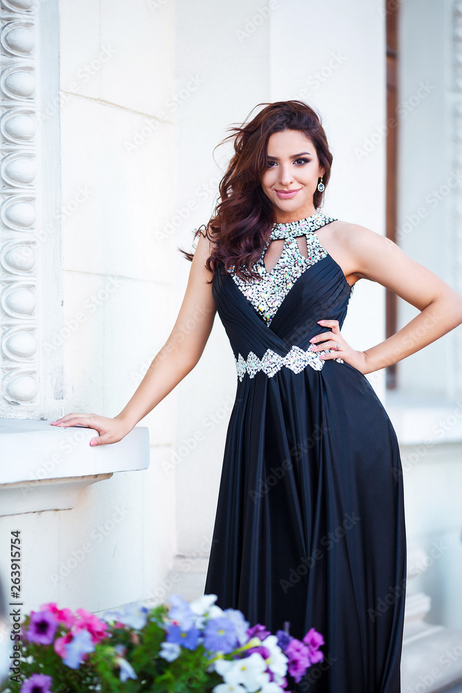 Fashion outdoor photo of beautiful sensual girl with dark hair in elegant dress posing in ancient architecture.