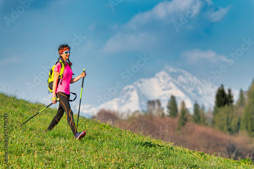 Young woman returning from a Nordic walking excursion in the mountains in spring