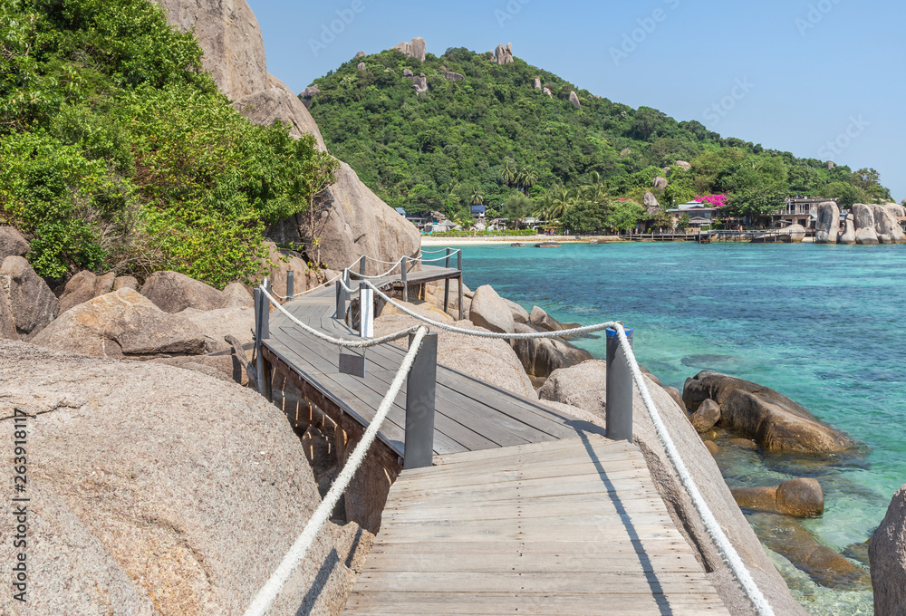 Fototapeta premium Landscape view of old wooden walkway bridge through the rock at Koh Nang Yuan Island under blue sky in summer day Koh Nang Yuan Island is most popular famous tourist attractions in the gulf of Thailan
