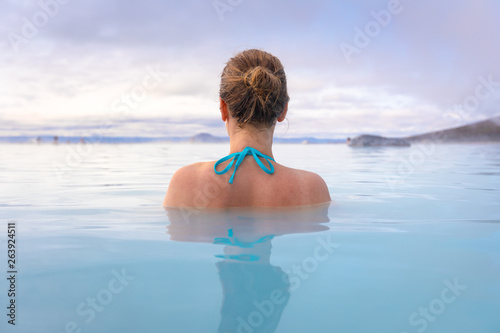 Geothermal spa in Iceland with young woman enjoying bathing in hot thermal pool with hotspring water for wellness and skin treatment, icelandic experience photo