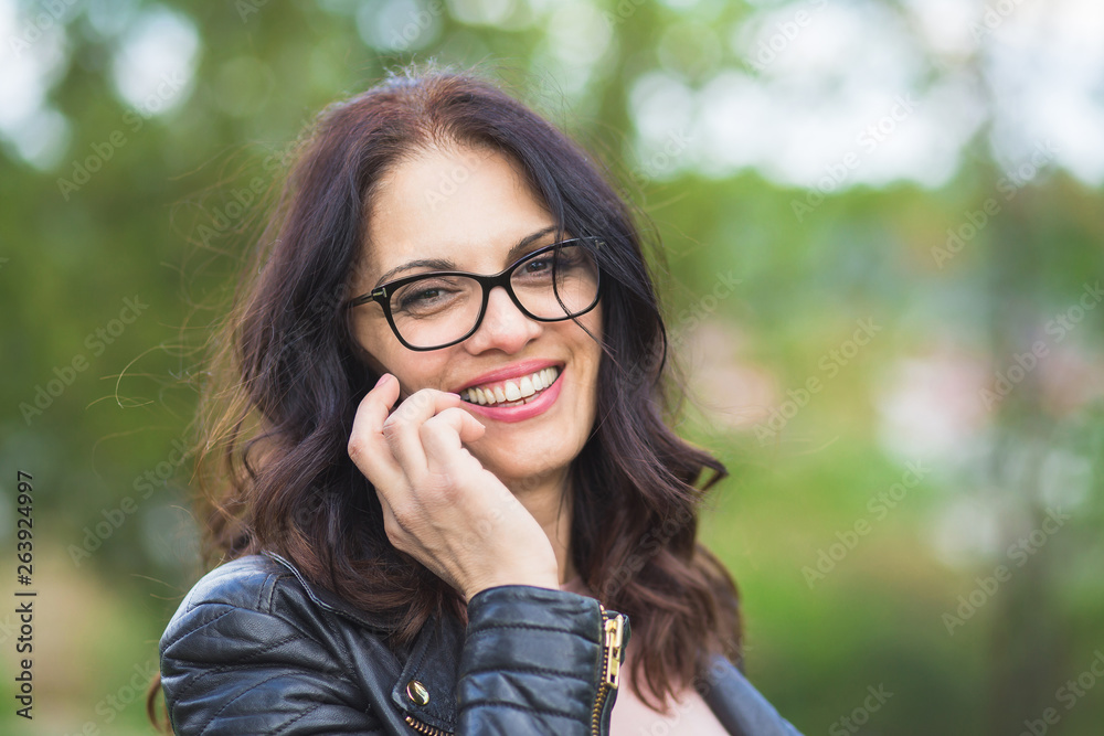 Beautiful middle-age woman in black leather jacket talking on the phone. Beautiful middle-age woman in black leather jacket talking on the phone.