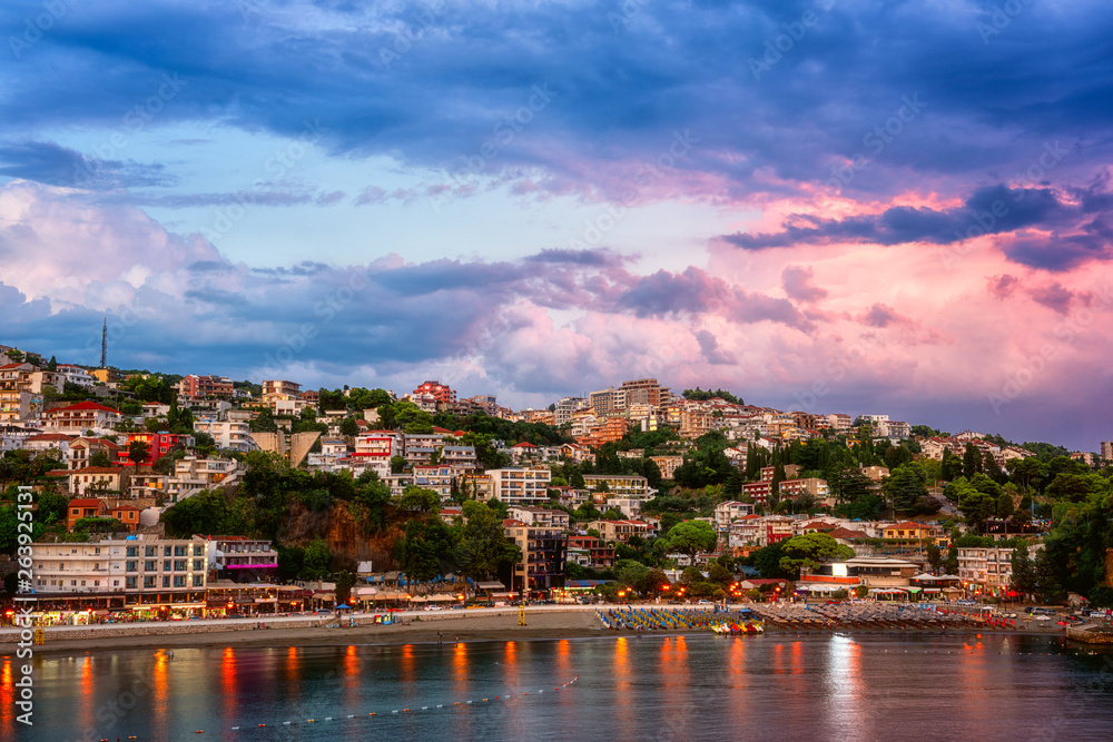 Panoramic view of Ulcinj at sunset, beautiful mediterranean town, popular summer tourist resort in Montenegro, scenic travel background with urban architecture, sand beach and dramatic cloudy sky