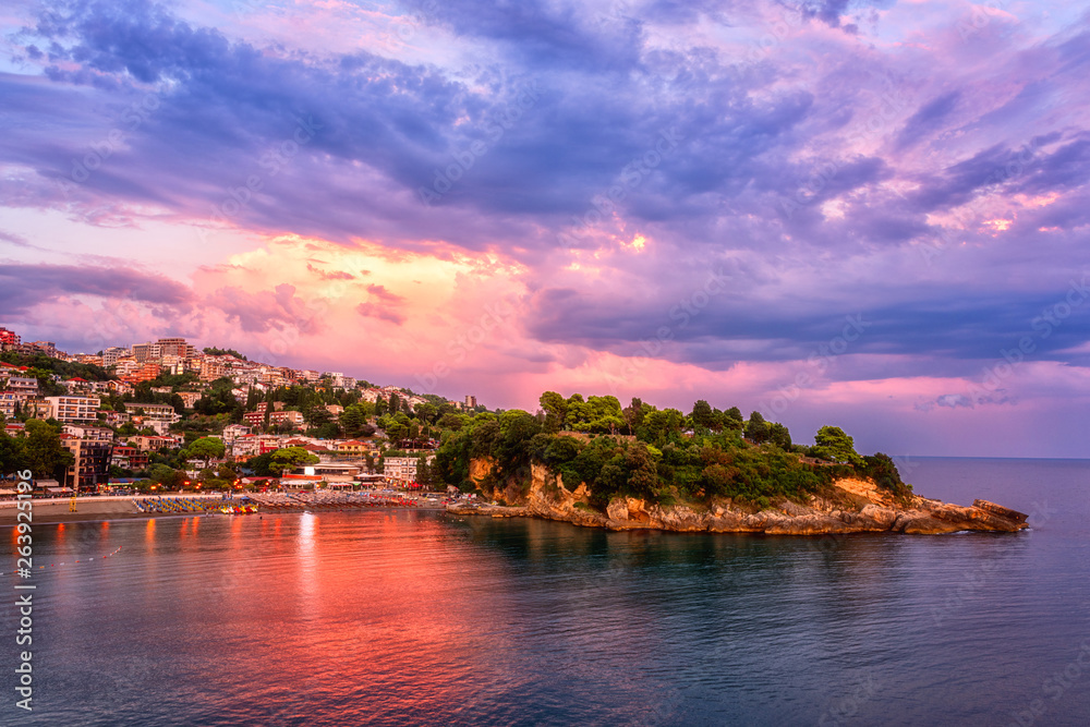 Panoramic view of Ulcinj and Jadran peninsula at sunset, beautiful mediterranean town, popular summer tourist resort in Montenegro, scenic travel background with amazing colorful cloudy sky