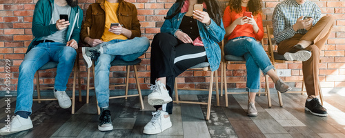 Millennials lifestyle. Group of young people sitting in modern loft office, using smartphones. Social media addiction.