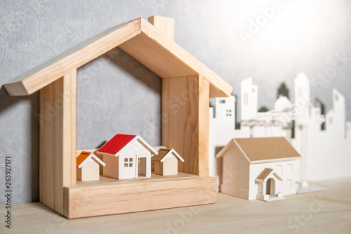 Property or real estate investment concept. Home mortgage loan rate. Saving money for future retirement. Miniature house model with paper city background and construction crane on wooden table.