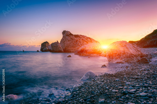 Aphrodite's Rock beach, Petra tou Romiou, the birthplace of Goddness Aphrodite, Paphos, Cyprus. Amazing sunset seascape of Love beach with rocks and sea pebbles, travel background, tourist location