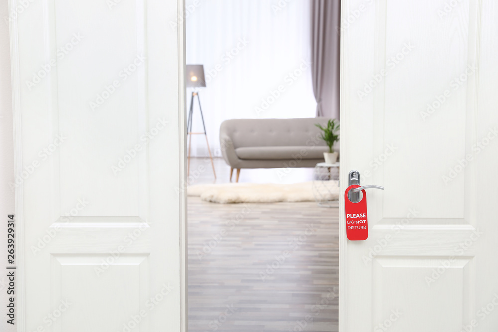 Fototapeta premium Open door with sign PLEASE DO NOT DISTURB on handle at hotel