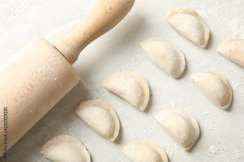 Raw dumplings and rolling pin on light background, top view. Process of cooking