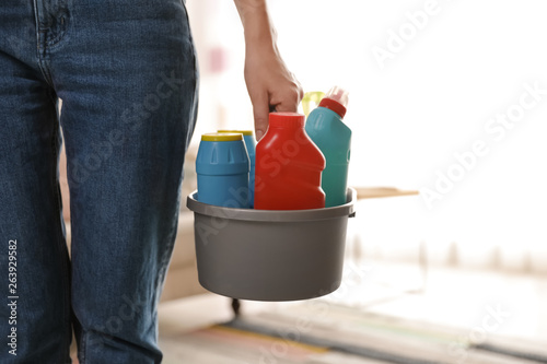 Woman with basket of professional cleaning products indoors, closeup. Space for text