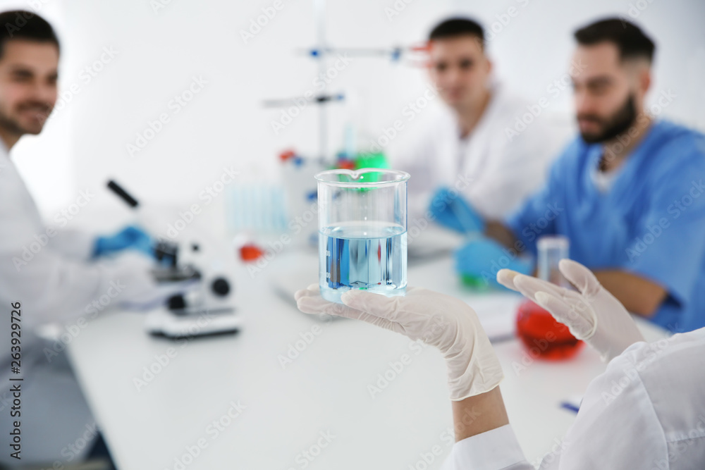 Medical student with beaker working in scientific laboratory