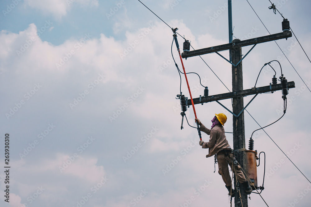 The power lineman use clamp stick (insulated tool) to closing a transformer on energized high-voltage electric power lines. The power lineman must be trained because it is a risky job. The power lineman use clamp stick (insulated tool) to closing a transformer on energized high-voltage electric power lines. The power lineman must be trained because it is a risky job.