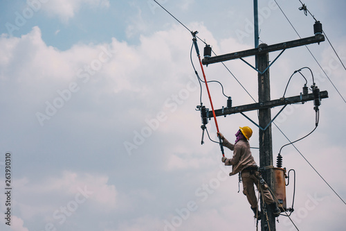 The power lineman use clamp stick (insulated tool) to closing a transformer on energized high-voltage electric power lines. The power lineman must be trained because it is a risky job.