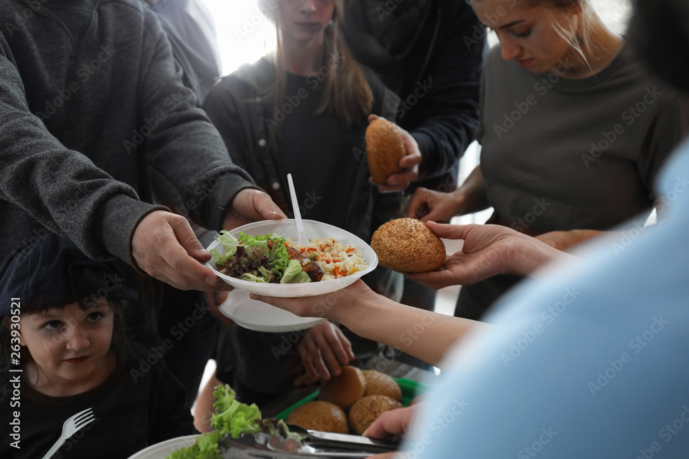 Poor people receiving food from volunteer indoors, closeup Poor people receiving food from volunteer indoors, closeup