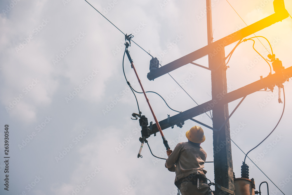 The power lineman use clamp stick (insulated tool) to closing a transformer on energized high-voltage electric power lines. The power lineman must be trained because it is a risky job. The power lineman use clamp stick (insulated tool) to closing a transformer on energized high-voltage electric power lines. The power lineman must be trained because it is a risky job.