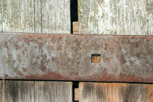 Texture of boards from the entrance door to the barn. On the boards you can see the trace of time through parallel cracks in the wood. Visible old rusty nails. Visible hinges