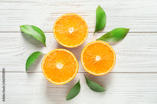 Fresh oranges with leaves on wooden background, flat lay