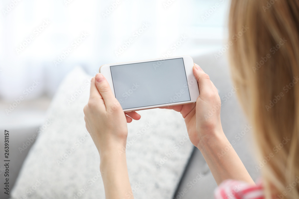 Young woman using video chat on smartphone in living room, closeup. Space for design