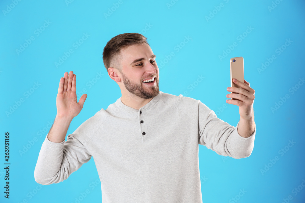 Young man using video chat on smartphone against color background Young man using video chat on smartphone against color background