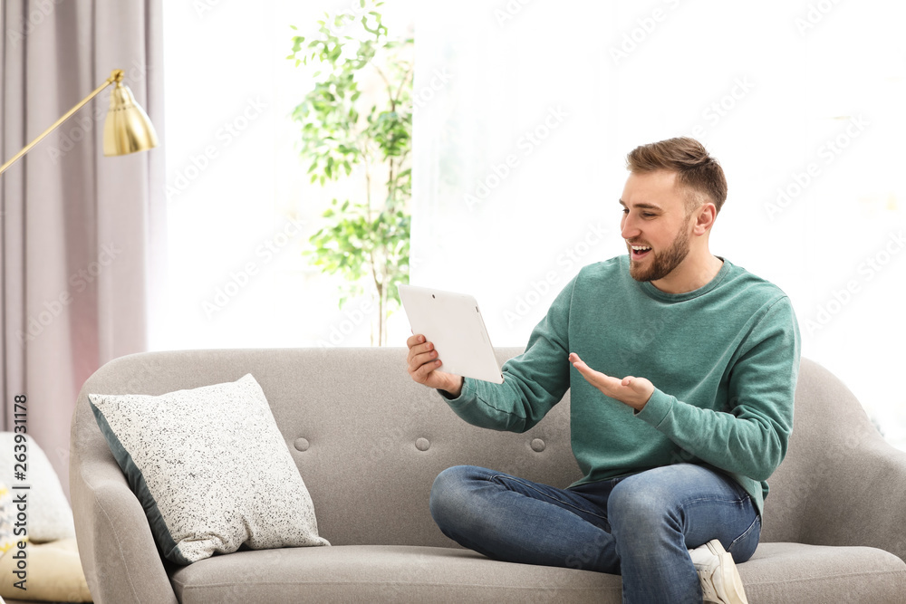 Young man using video chat on tablet in living room Young man using video chat on tablet in living room