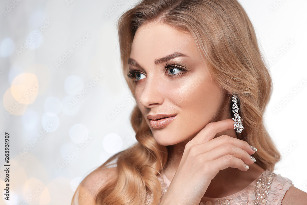 Fototapeta premium Beautiful young woman with elegant jewelry against defocused lights. Space for text