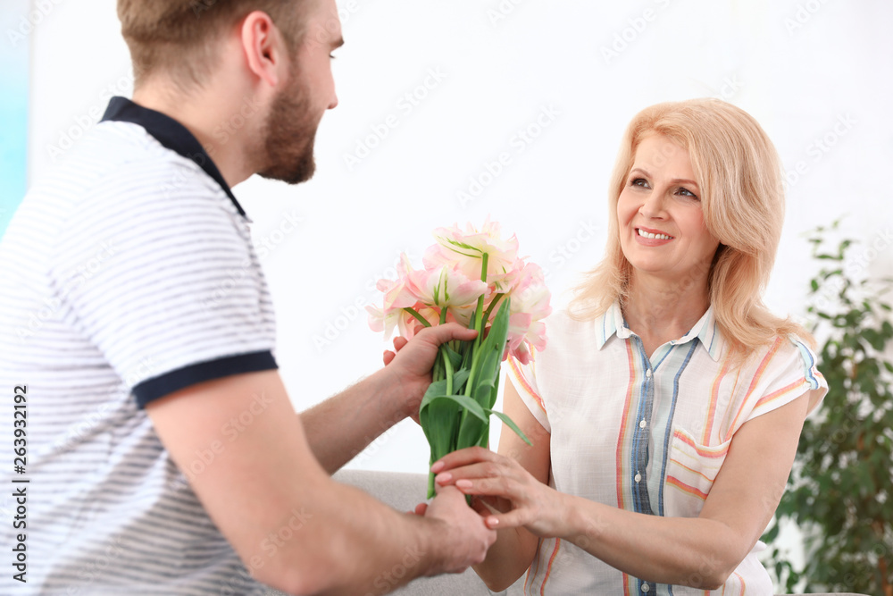 Young man congratulating his mature mom at home. Happy Mother's Day Young man congratulating his mature mom at home. Happy Mother's Day