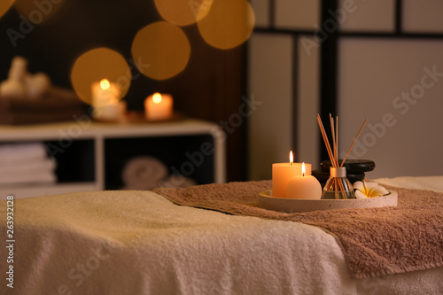 Burning candles and aromatic reed freshener on table in spa salon, space for text photo