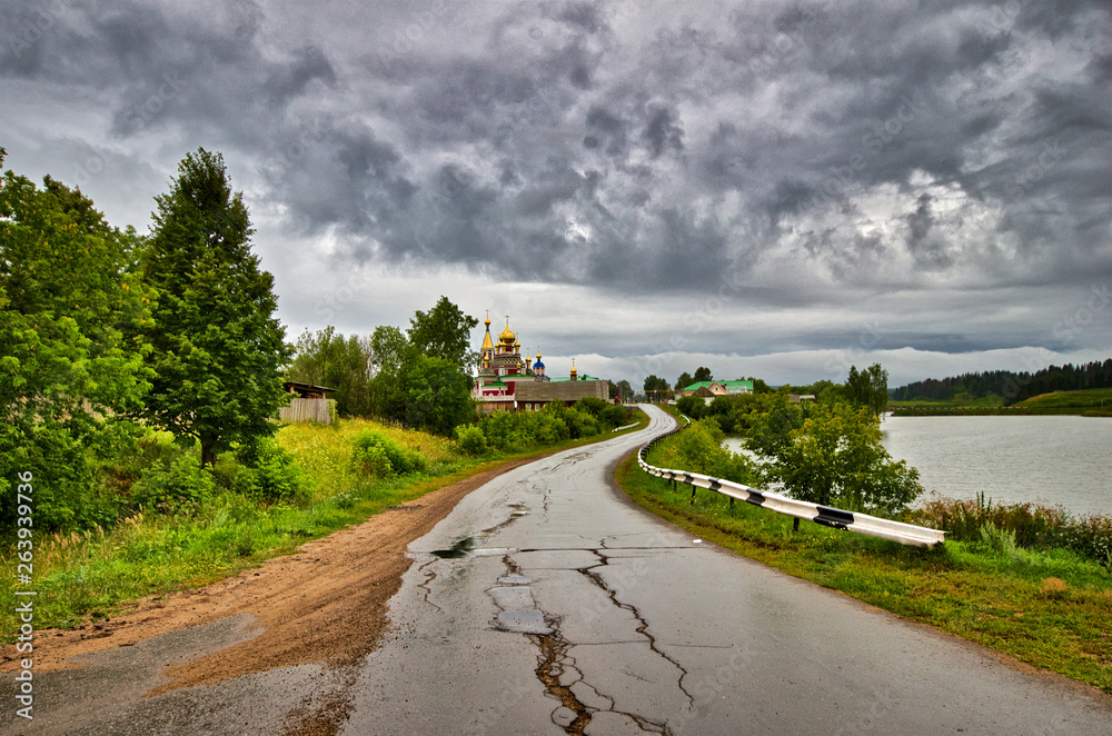 Fototapeta premium Old broken asphalt road in the village with the temple