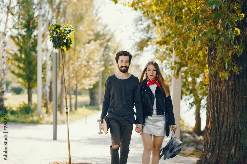 young hipsters standing in a summer sunny park with a skateboard in their hands young hipsters standing in a summer sunny park with a skateboard in their hands