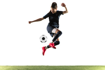 Female soccer player kicking ball isolated over white background