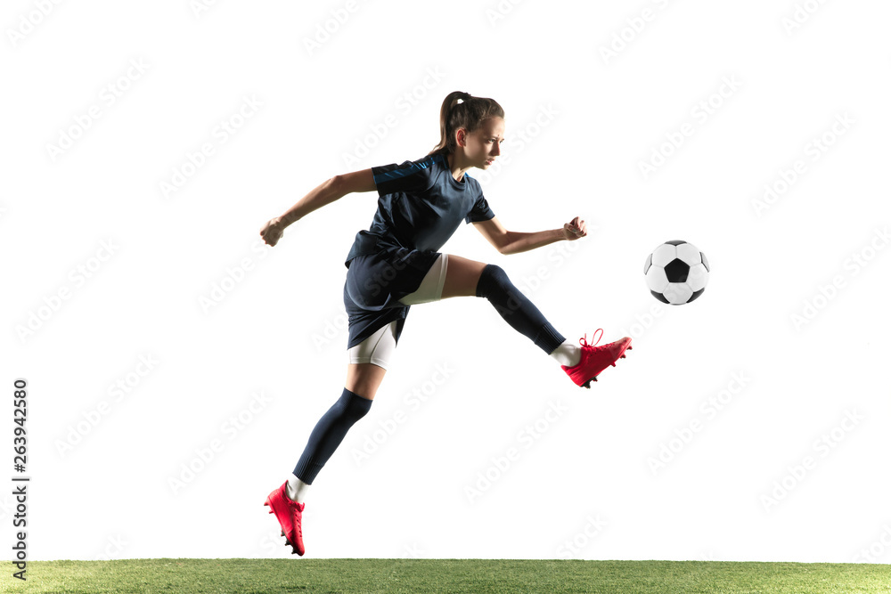 Female soccer player kicking ball isolated over white background